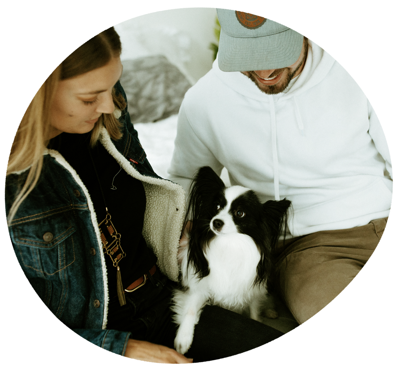 black and white dog sitting with two people